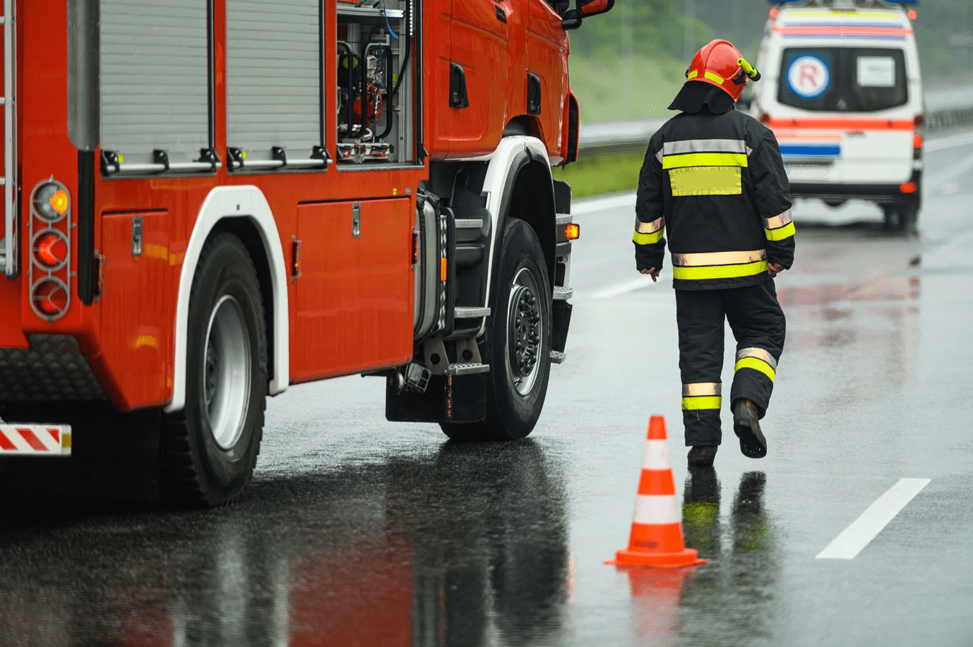 Bild mit einem Feuerwehrmann und einem Feuerwehrwagen mit einem Krankenwagen im Hintergrund